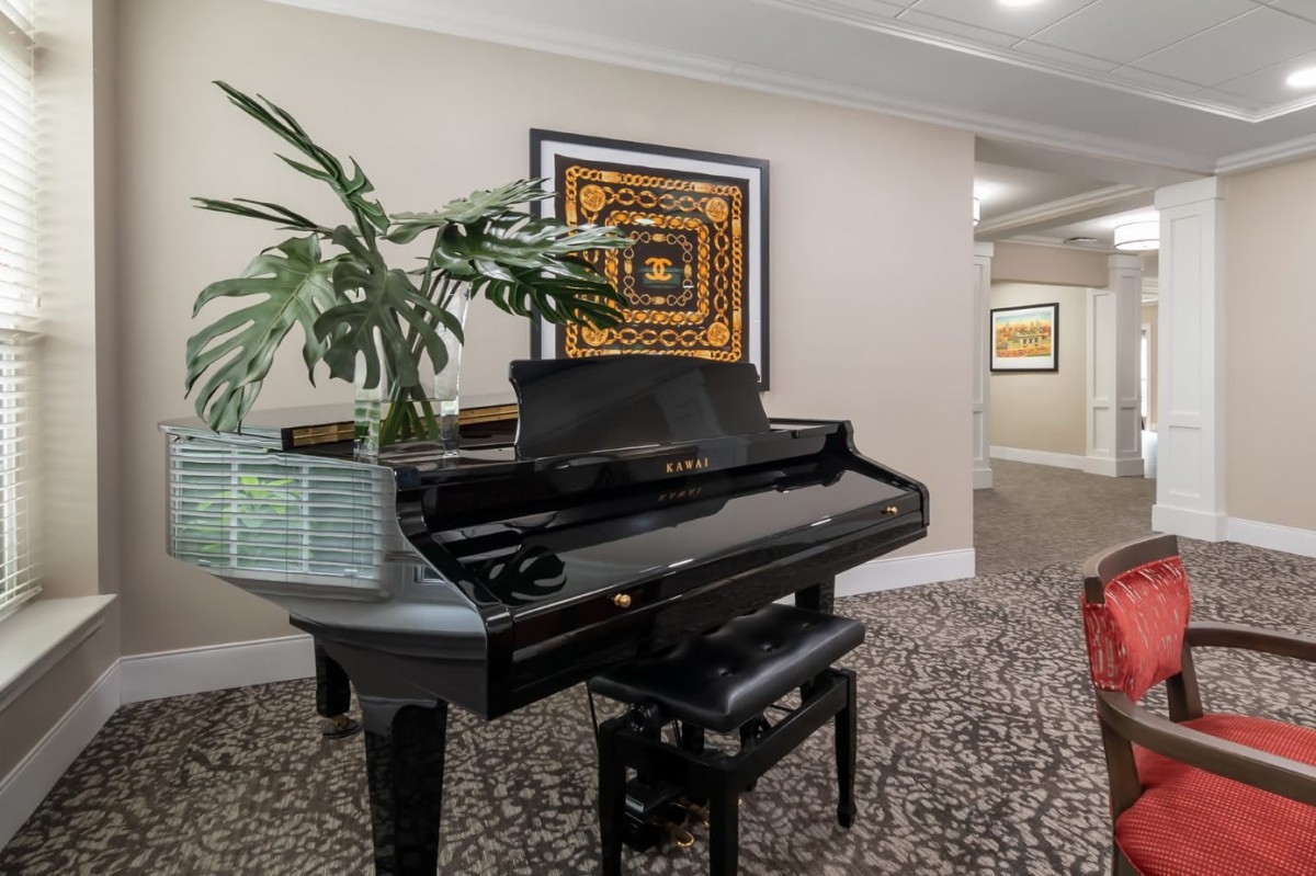 A grand piano in a stylish hallway with artwork and plants.