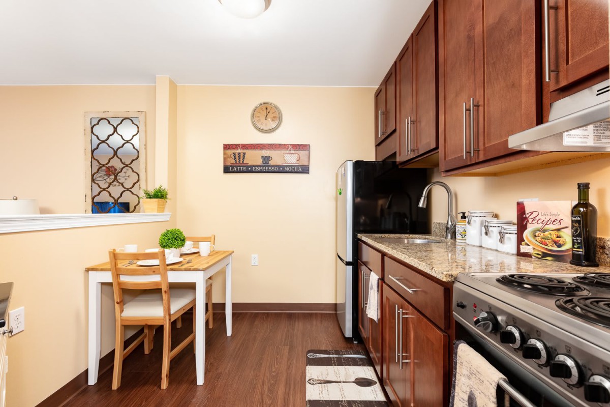 A cozy kitchen with wooden cabinets, stainless steel appliances, and a small dining area.