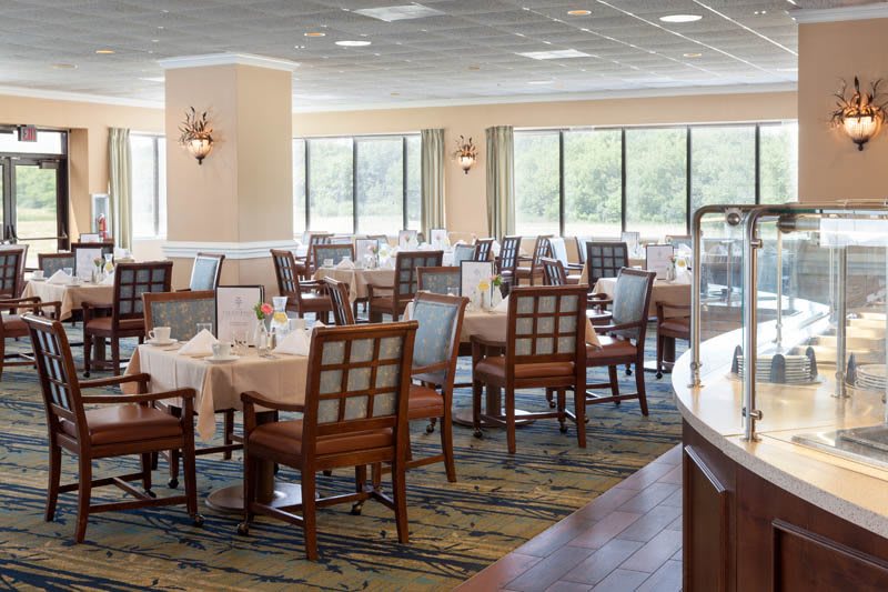 A spacious and well-lit restaurant dining area with neatly arranged tables and chairs.