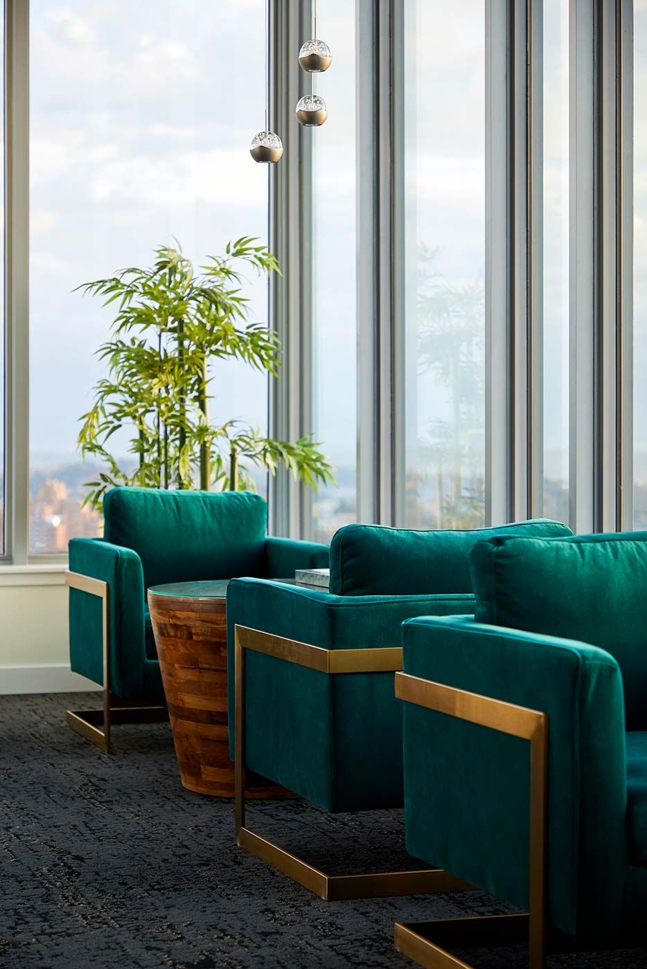 A modern office seating area with green armchairs and large windows.