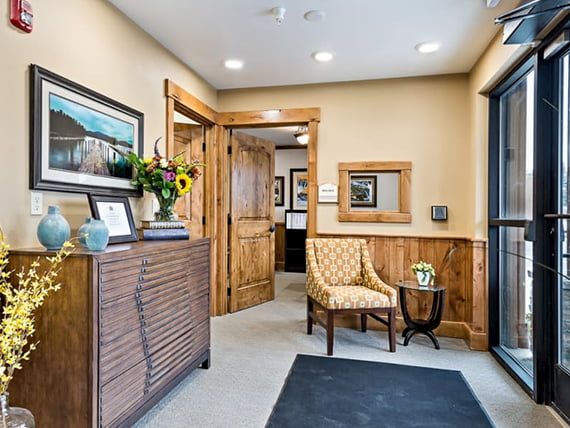 A cozy reception area with wooden accents, featuring wall art and a comfortable chair.