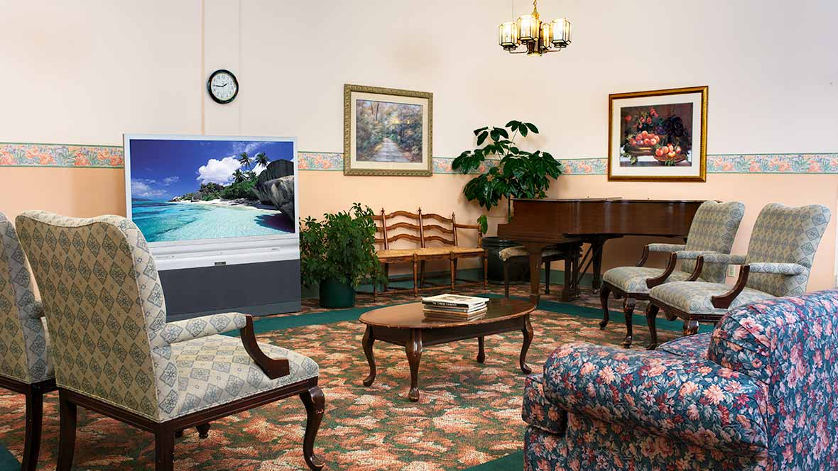 A cozy living room featuring a piano, artwork, and comfortable seating.