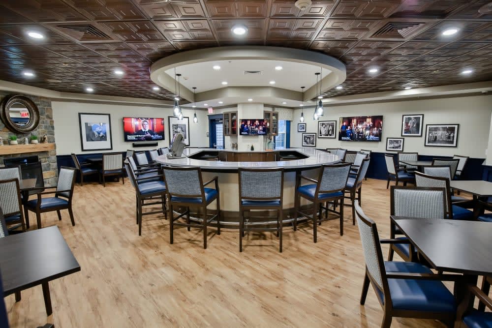 A modern bar area with circular seating, multiple TVs, and stylish lighting.