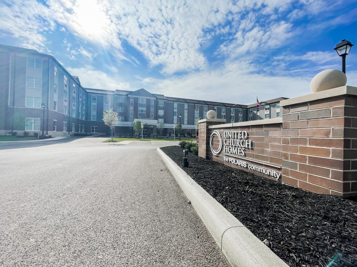 A hotel building under a partly cloudy sky with a driveway leading up to it.