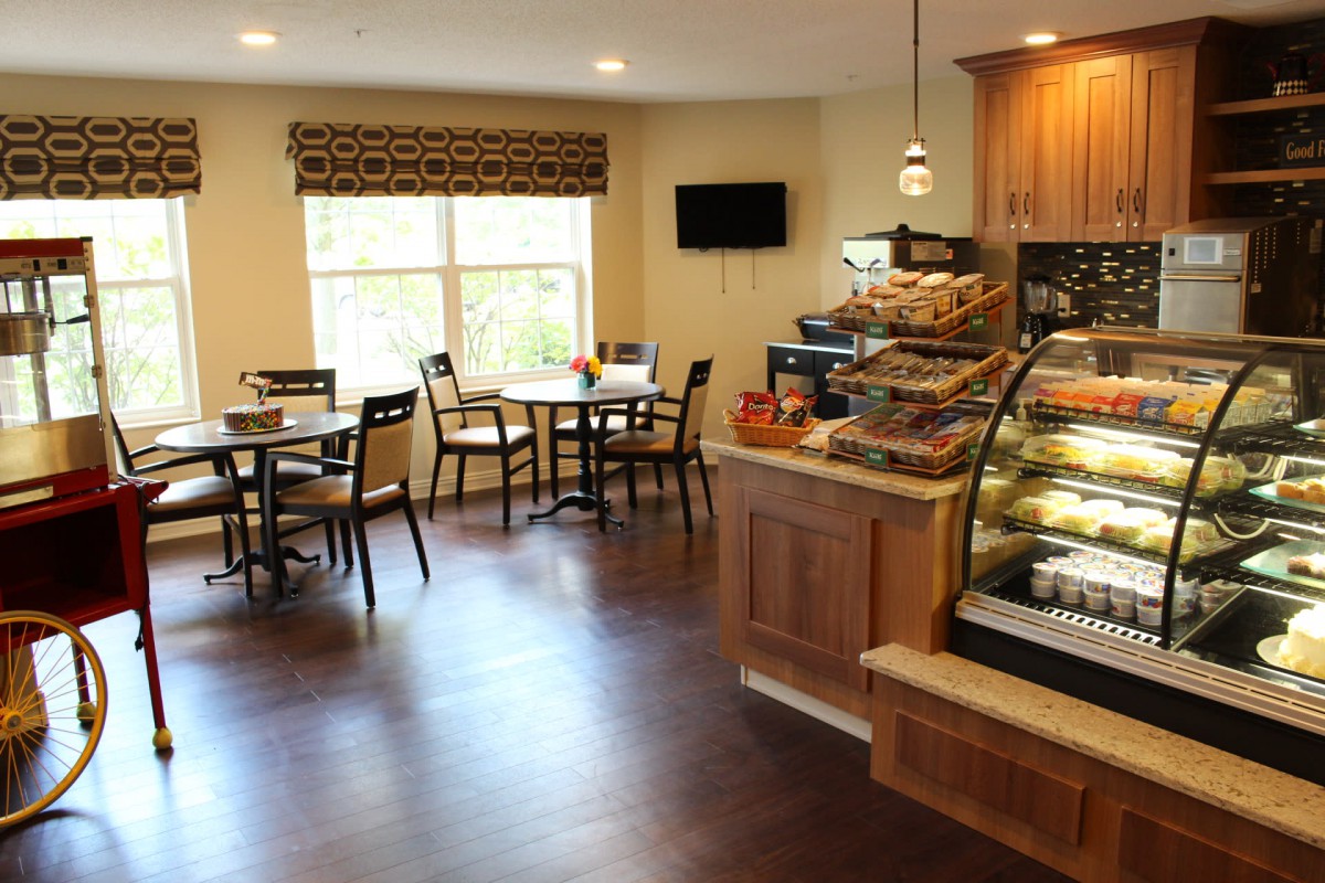 A cozy cafe interior featuring tables and chairs, a pastry display, and a warm atmosphere.