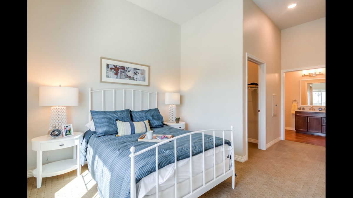 A modern and cozy bedroom with a minimalist design, featuring a neatly made bed with blue bedding and subtle decor.
