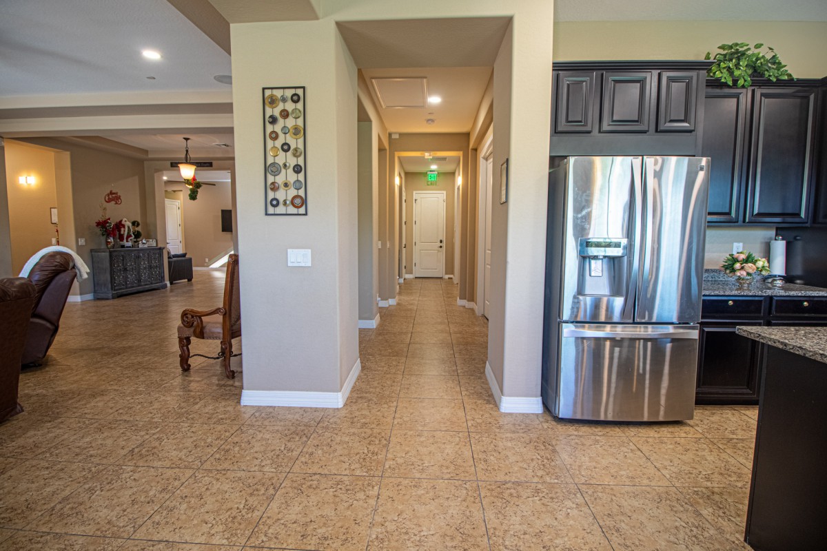 A modern kitchen with a stainless steel refrigerator and a long hallway.