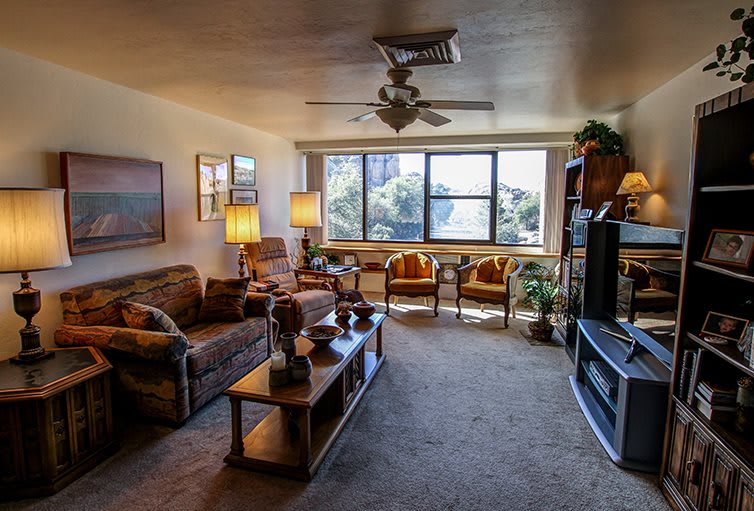 A cozy living room with comfortable seating, large windows, and warm lighting.