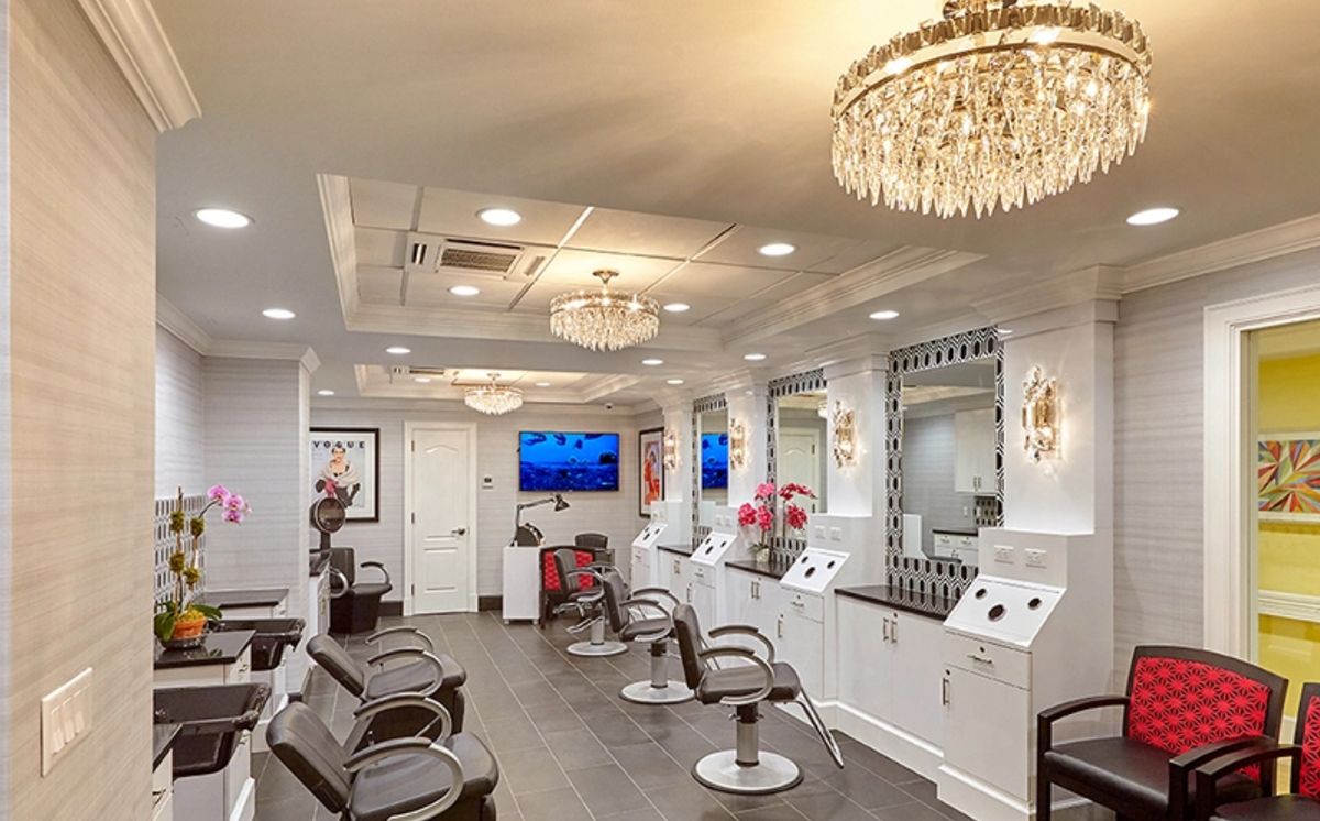 A luxurious modern salon interior with chandeliers and seating areas.