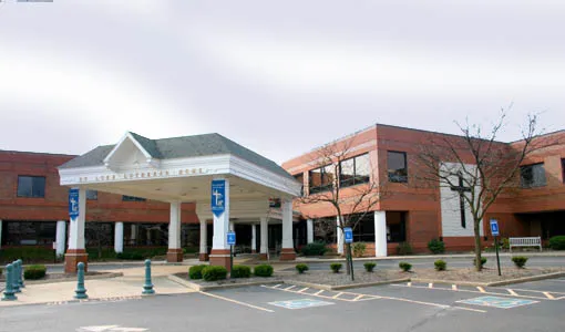 The exterior of a hospital building with an entrance canopy and accessible parking spaces.