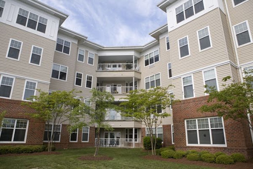 A modern apartment building with multiple floors and balconies, surrounded by greenery.