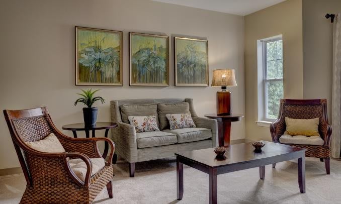 A cozy living room with a sofa, armchairs, and decorative wall art.