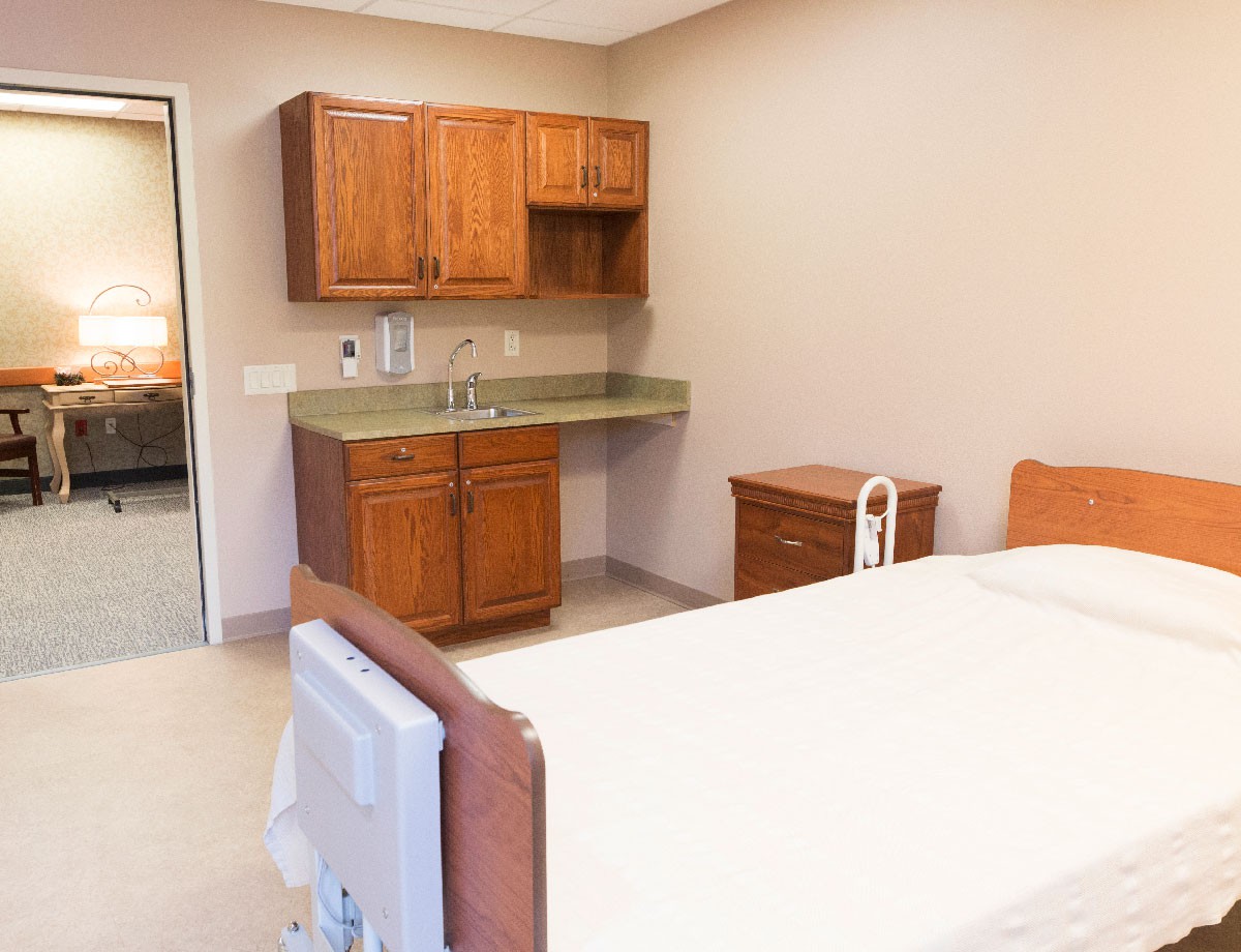 A clean and well-organized hospital room with a bed, cabinets, and a sink.