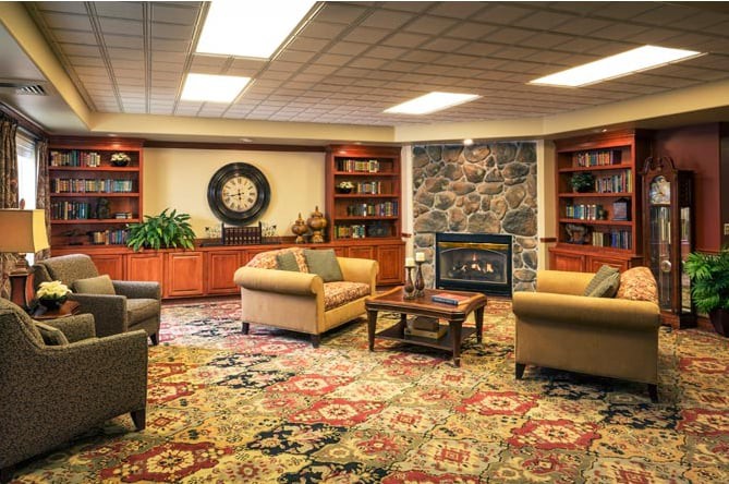 A cozy living room with comfortable sofas, a stone fireplace, and bookshelves lining the walls.