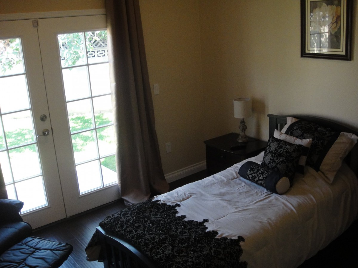 A cozy bedroom with a single bed and French doors leading outside.