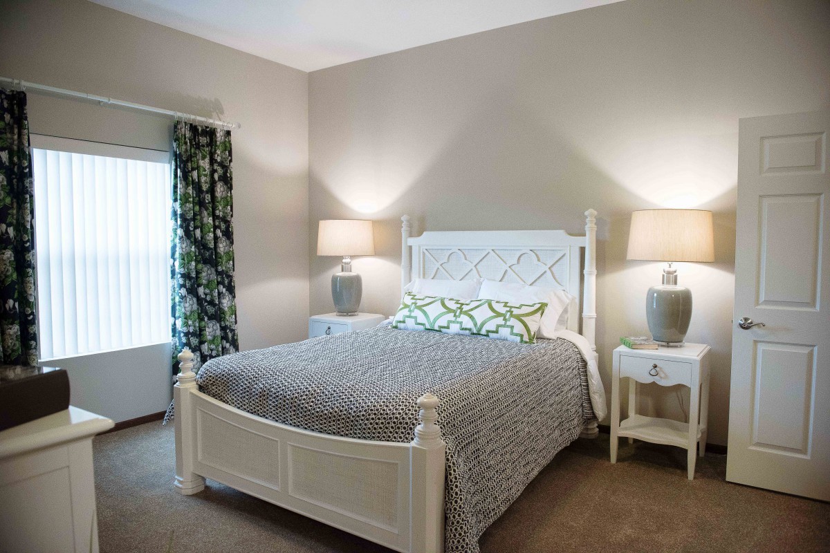 A cozy bedroom with a white bed, patterned bedding, and two lamps on nightstands.