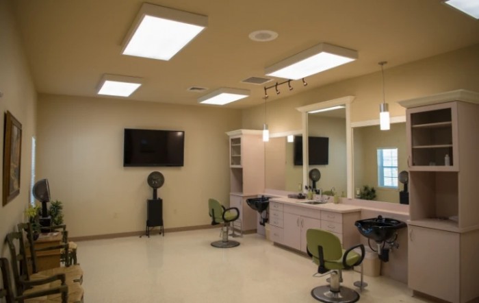 An empty hair salon interior with styling stations, chairs, and bright lighting.