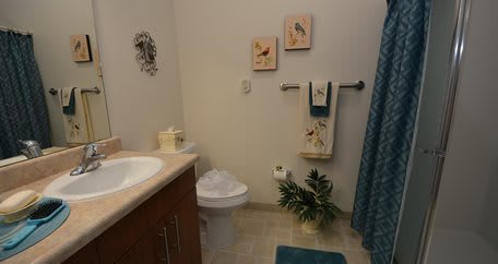 A neatly decorated bathroom with towels, plants, and wall art.