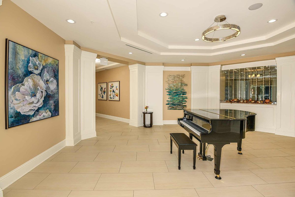 A modern hallway featuring a grand piano and various artworks on the walls.