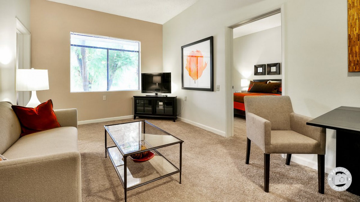 A modern living room with a coffee table, television, and artwork on the wall.