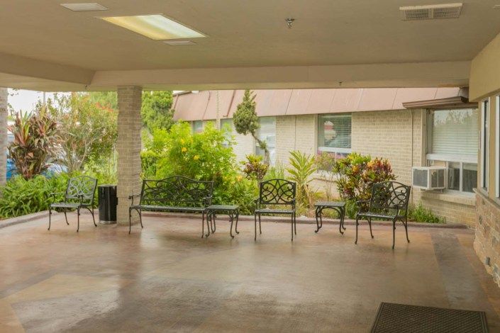 A covered patio area with benches overlooking a garden.