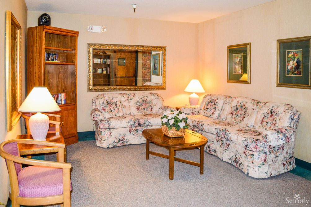 A cozy living room with floral sofas and warm lighting.