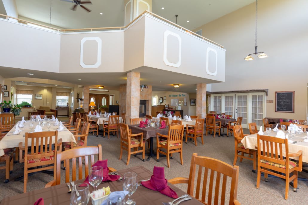 Elegant dining area with neatly arranged tables and chairs, adorned with colorful napkins.