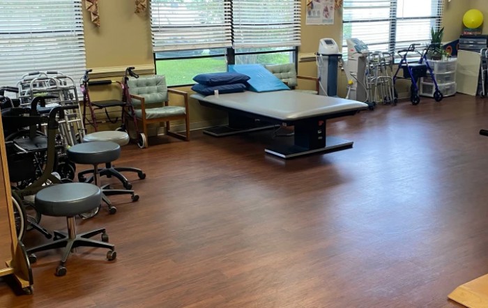 A clean and organized physical therapy room with a treatment table and chairs.