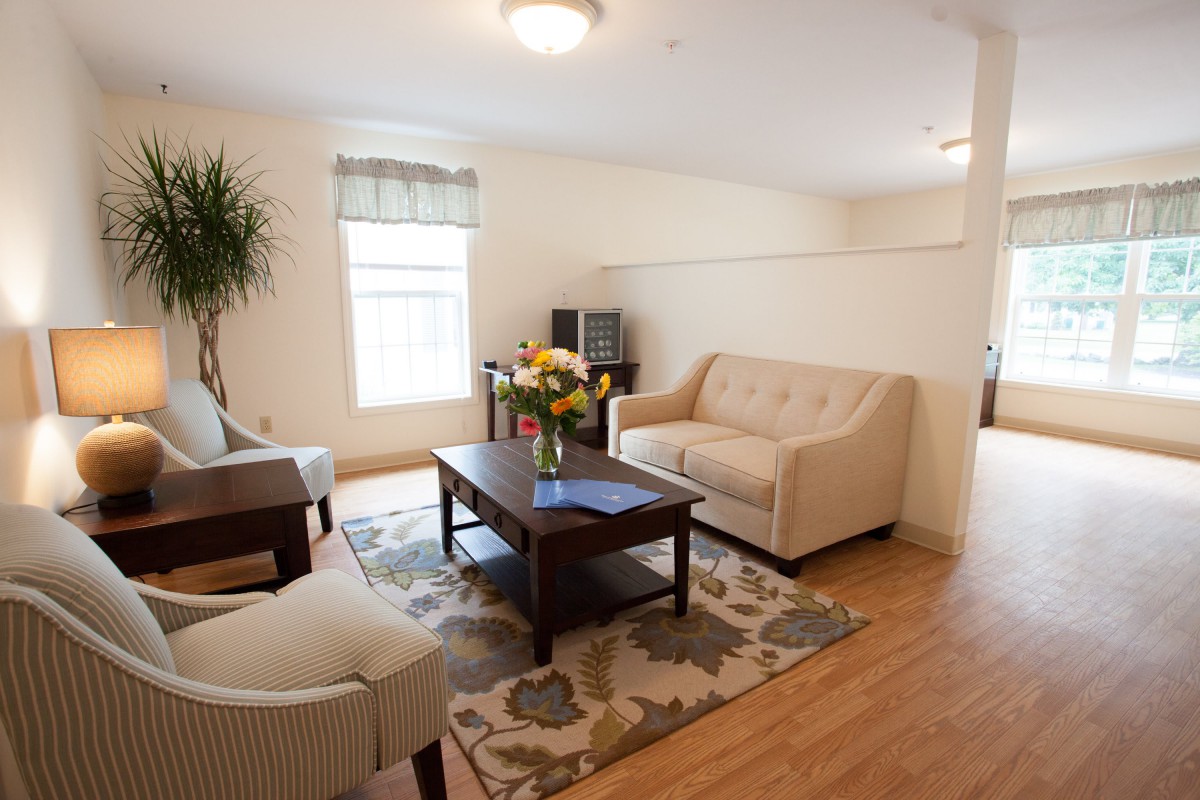A cozy living room with a sofa, armchairs, and a coffee table on a decorative rug.