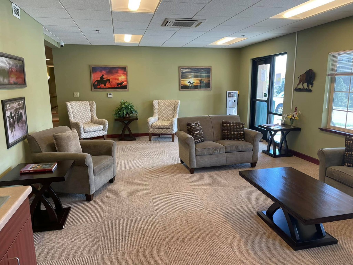 A comfortable waiting room with sofas, armchairs, and a coffee table.