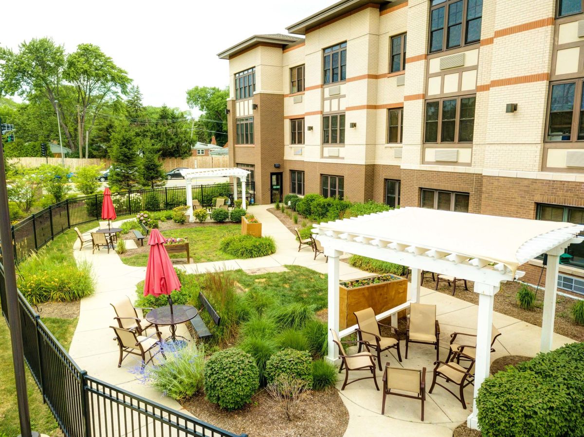 A beautifully landscaped garden with outdoor seating areas and umbrellas in front of a modern building.