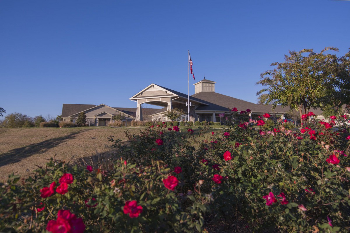 A scenic view of a building surrounded by vibrant red roses under a clear blue sky.