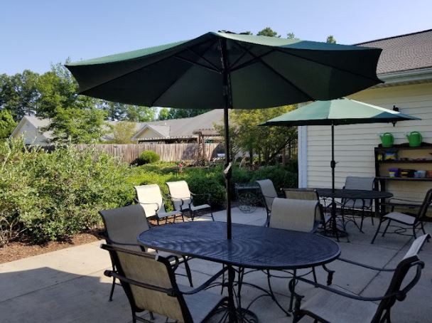 A sunny patio with outdoor furniture and umbrellas in a backyard setting.