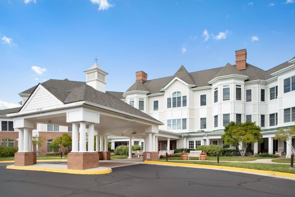 A large, well-maintained residential building with a covered entrance and surrounding greenery.