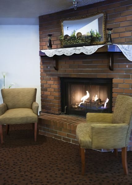 A cozy indoor setting with a brick fireplace and two comfortable chairs.