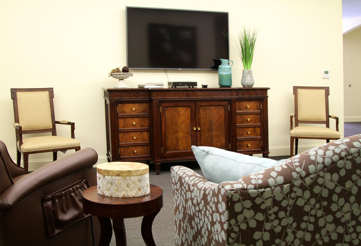 A cozy living room with a television mounted above a wooden cabinet and comfortable seating.