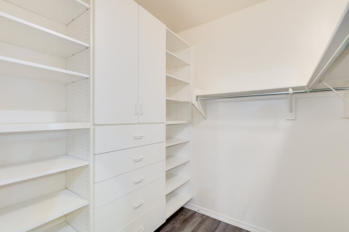 A spacious walk-in closet with white shelving and storage units.