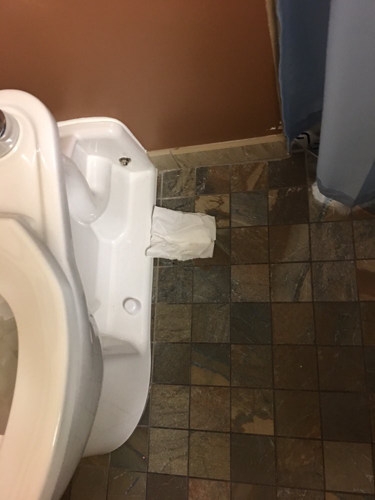 A restroom urinal with toilet paper awkwardly placed on its side.