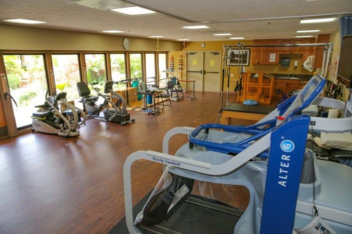 A spacious gym featuring a variety of exercise and rehabilitation equipment.