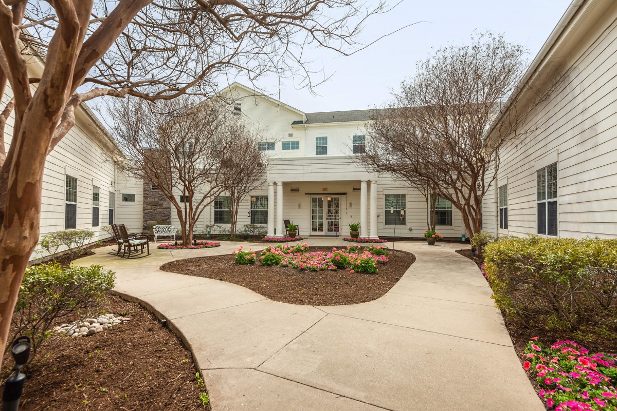 A welcoming entrance to a two-story residential building with well-maintained landscaping.