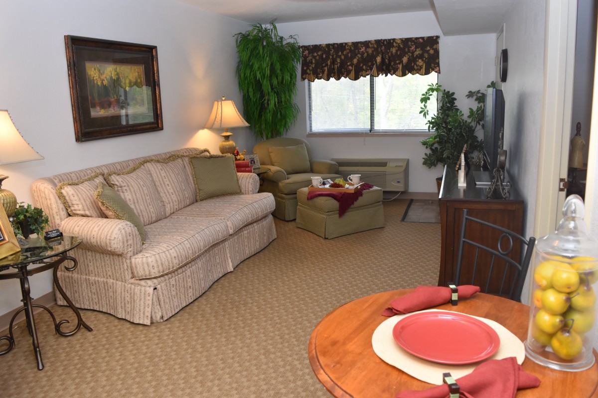 A cozy living room with a sofa, armchair, and neatly set table.