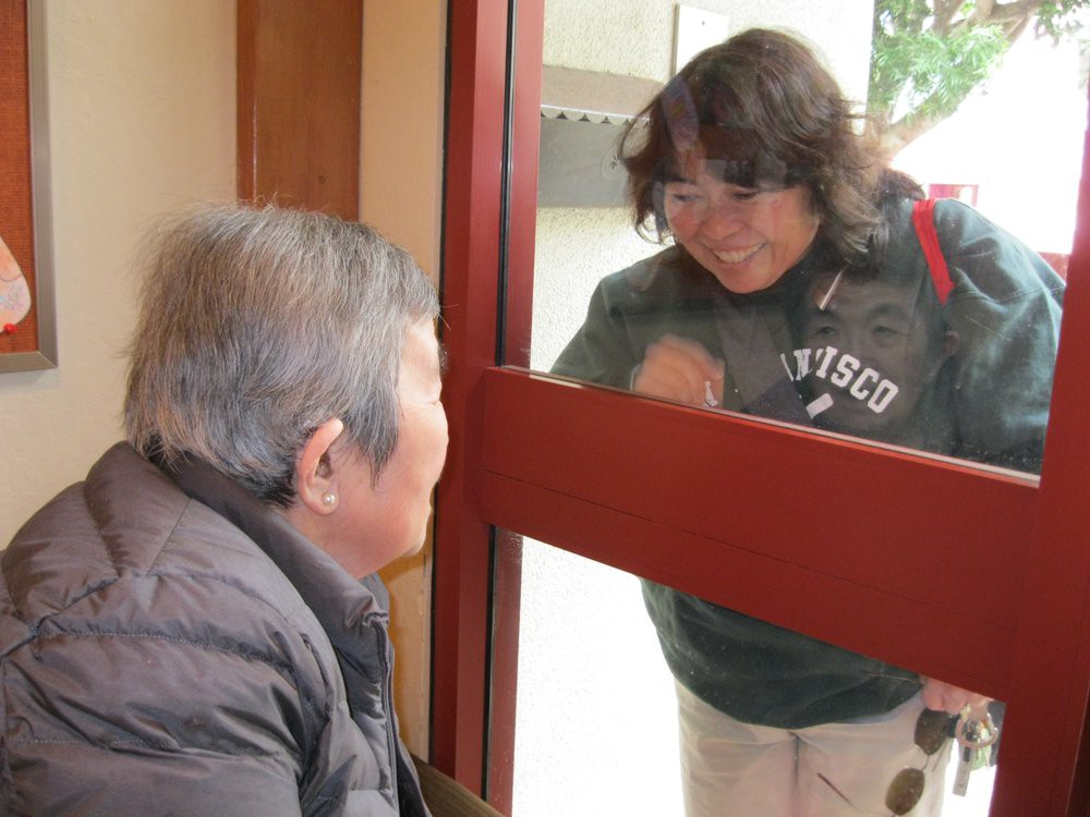 Two people interacting through a window, one indoors and the other outdoors.