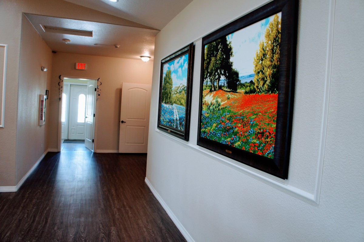 A hallway featuring vibrant landscape paintings on the wall, creating an inviting atmosphere.