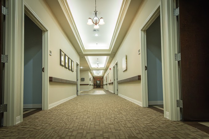 A well-lit hallway with doors on either side and carpeted flooring.