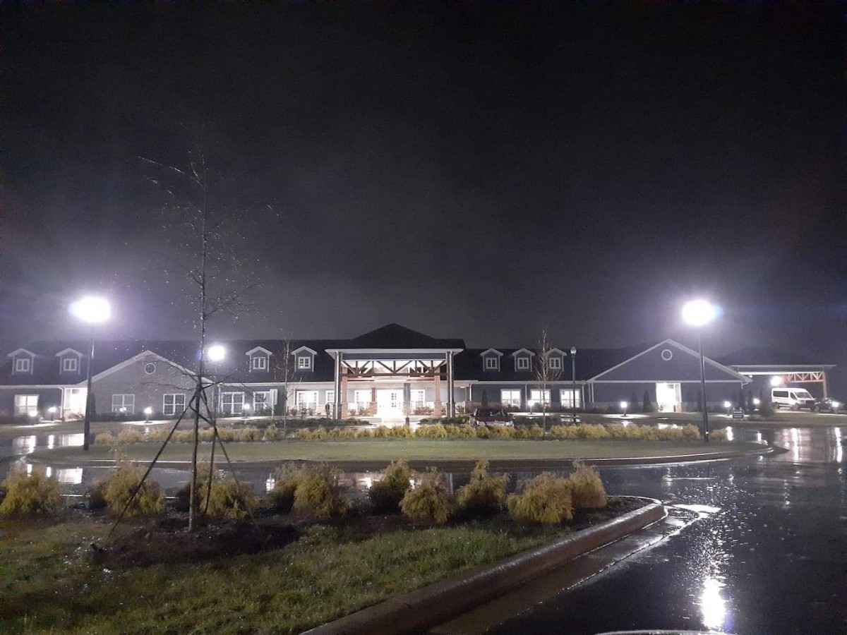 A well-lit building captured at night with reflections on the wet ground.