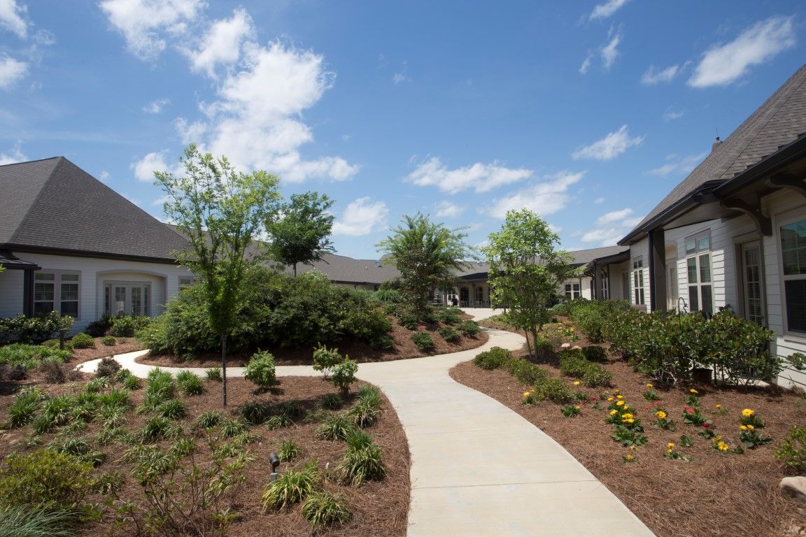 A sunny day in a landscaped residential courtyard with winding pathways and lush greenery.