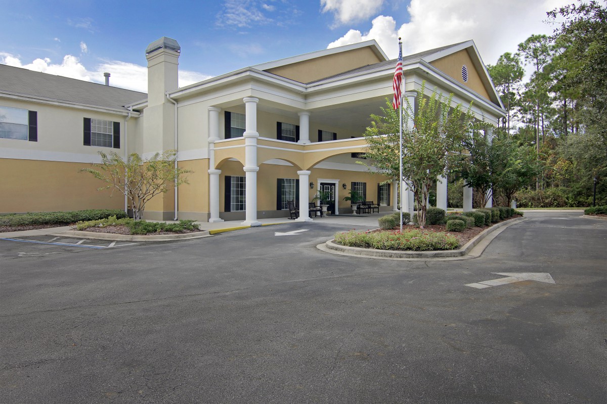 Front view of a building with columns, flagpole, and surrounding landscaping.