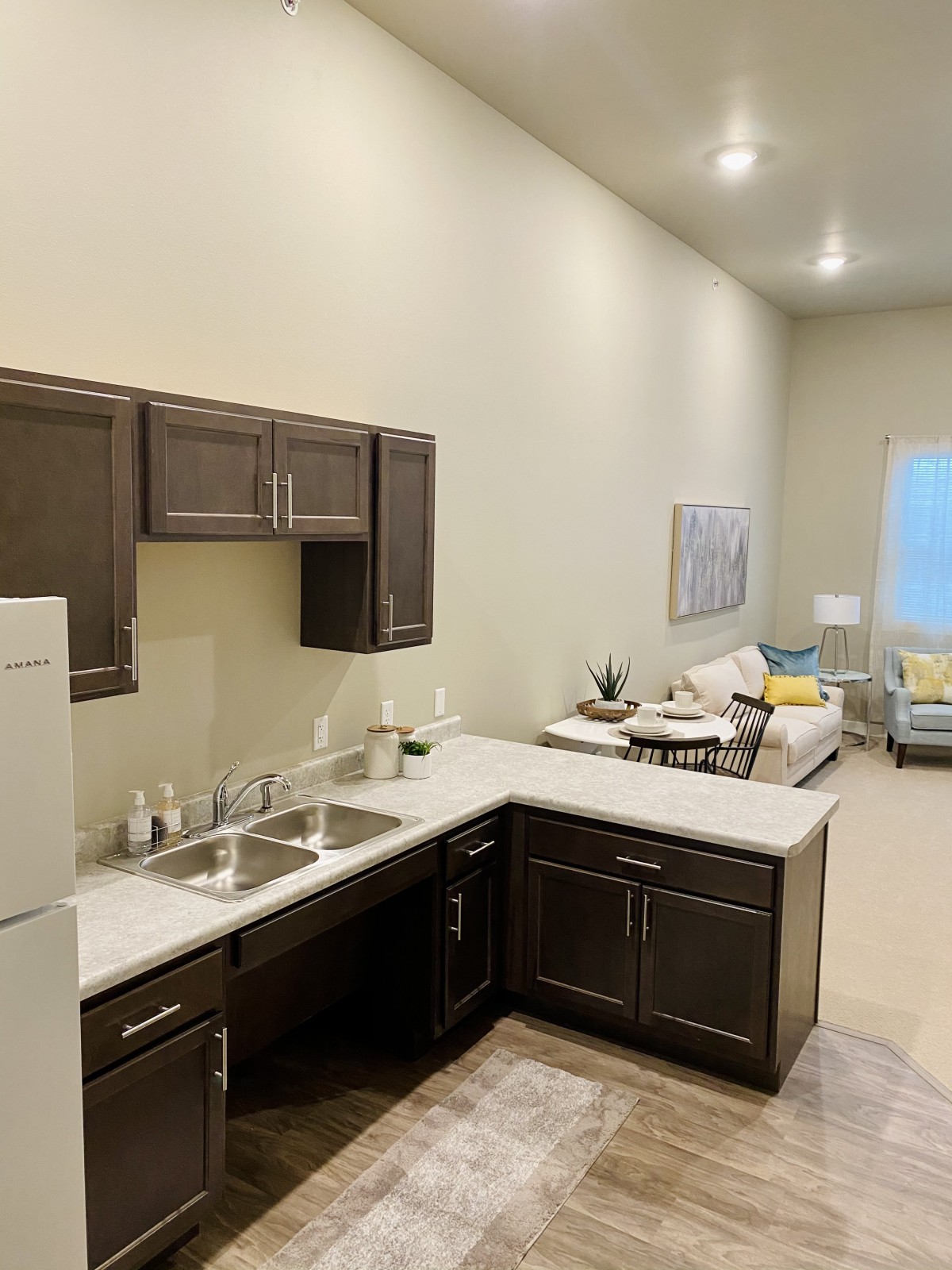 A modern open-concept kitchen and living area with dark cabinets and neutral tones.