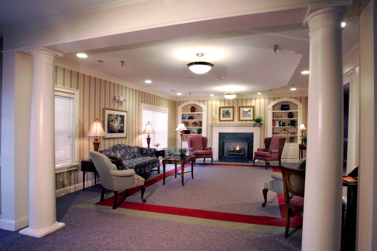 A cozy living room featuring traditional decor with a fireplace, elegant armchairs, and a sofa.