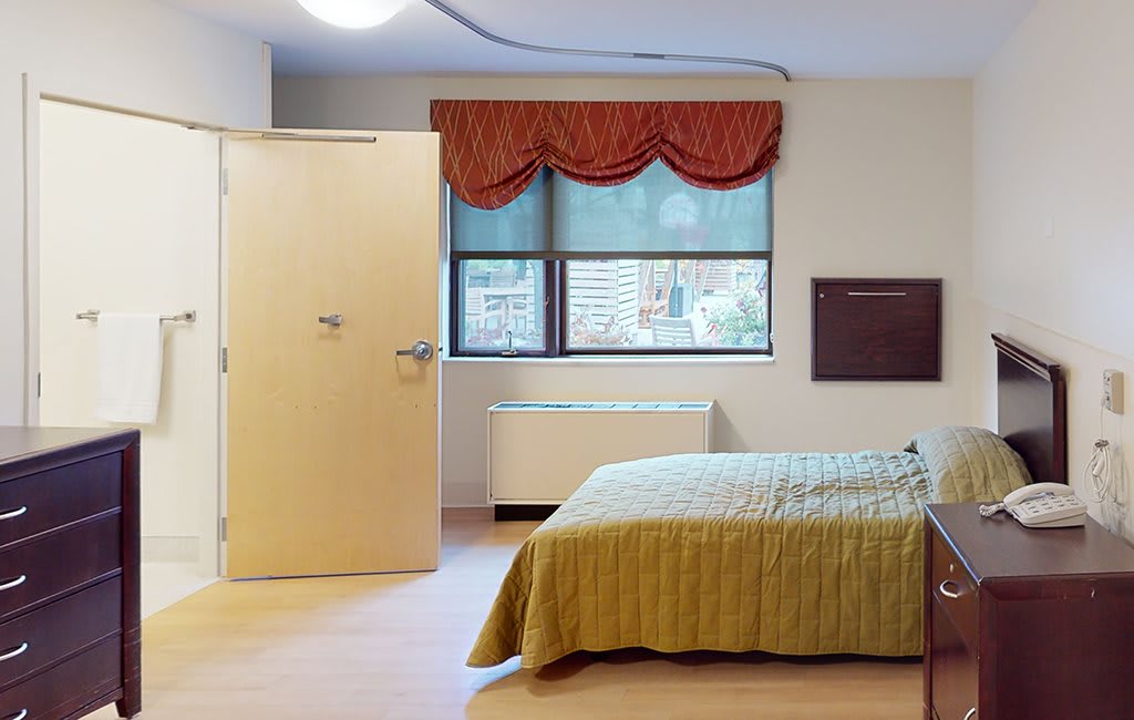 A hospital room with a bed, window, and privacy curtains.